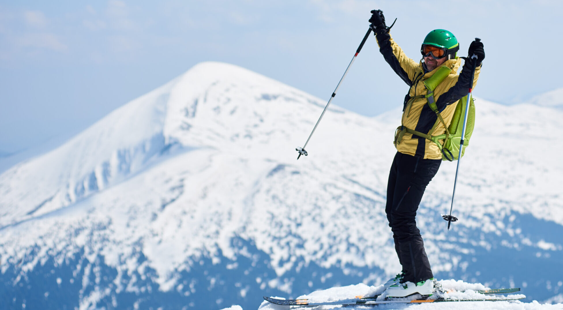 Sportsman skier on skis on background of blue sky and highland landscape. Winter skiing concept.