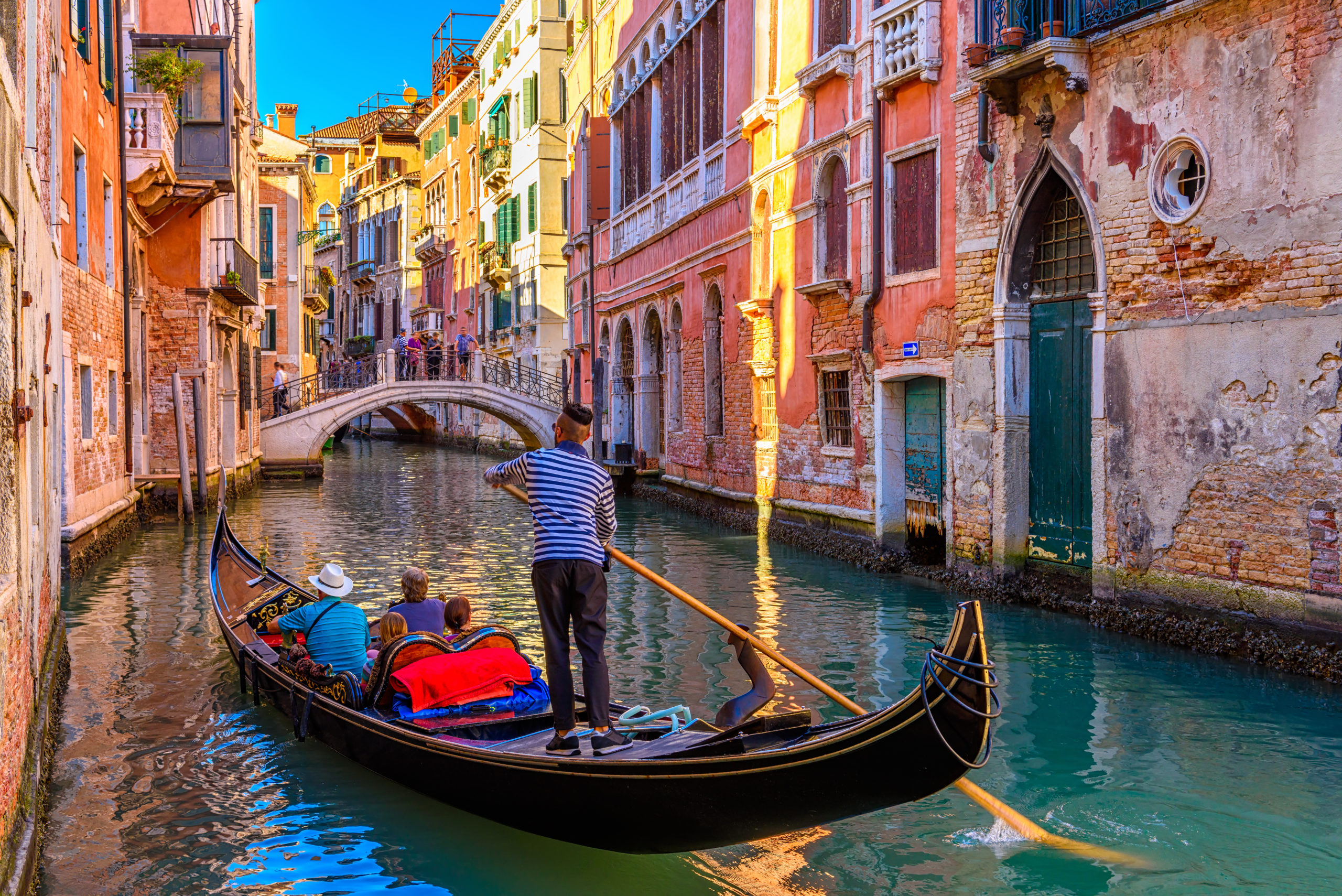 Narrow canal with gondola and bridge in Venice, Italy. Architect